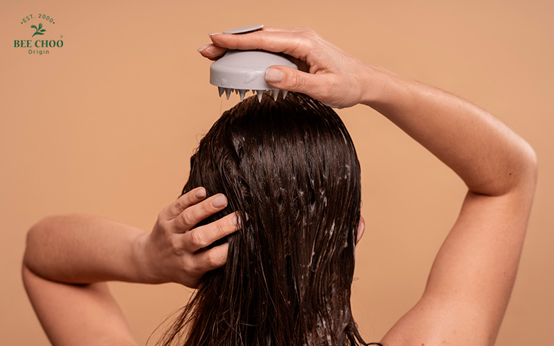 A person using a scalp massager on their hair in the shower.
