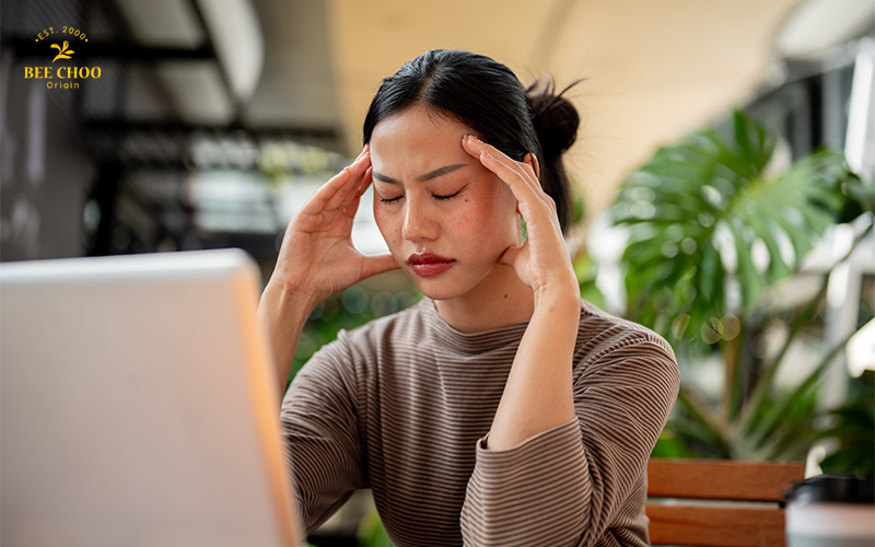 Why Do I Have Dandruff? Reasons and How to Stop It 2 A woman with a headache at her laptop.