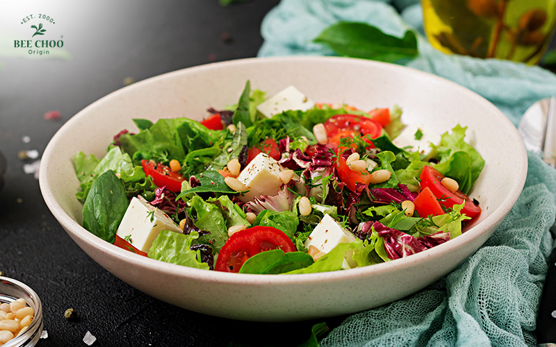 Fresh salad with cheese, tomatoes, and pine nuts.