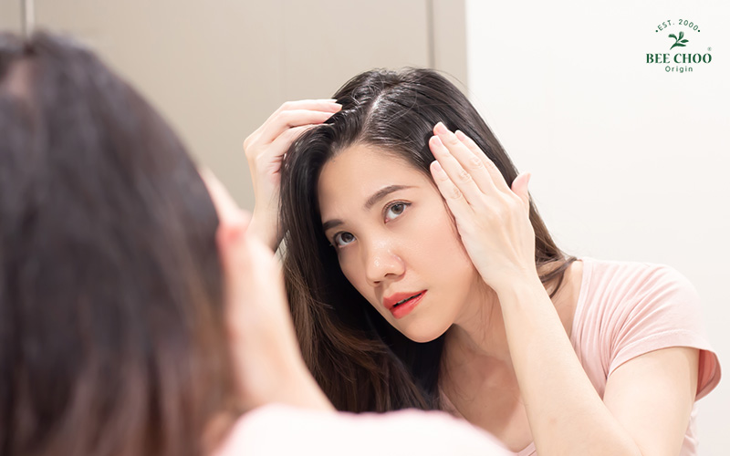 Woman checking hair loss in mirror.