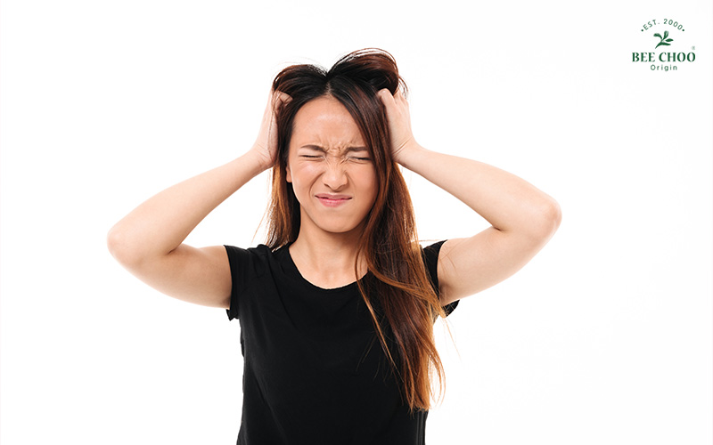 Woman frustrated by excess sebum on her scalp.