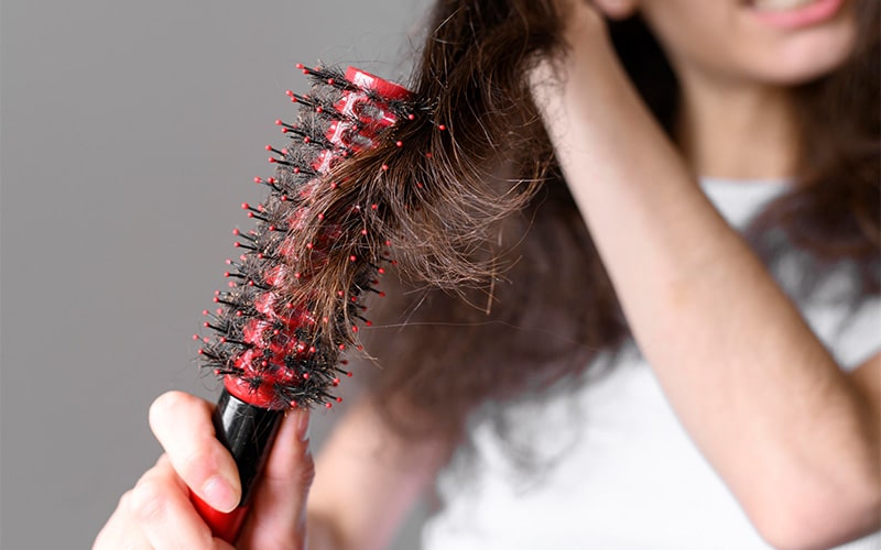 clump of loose hair caught on a red hairbrush